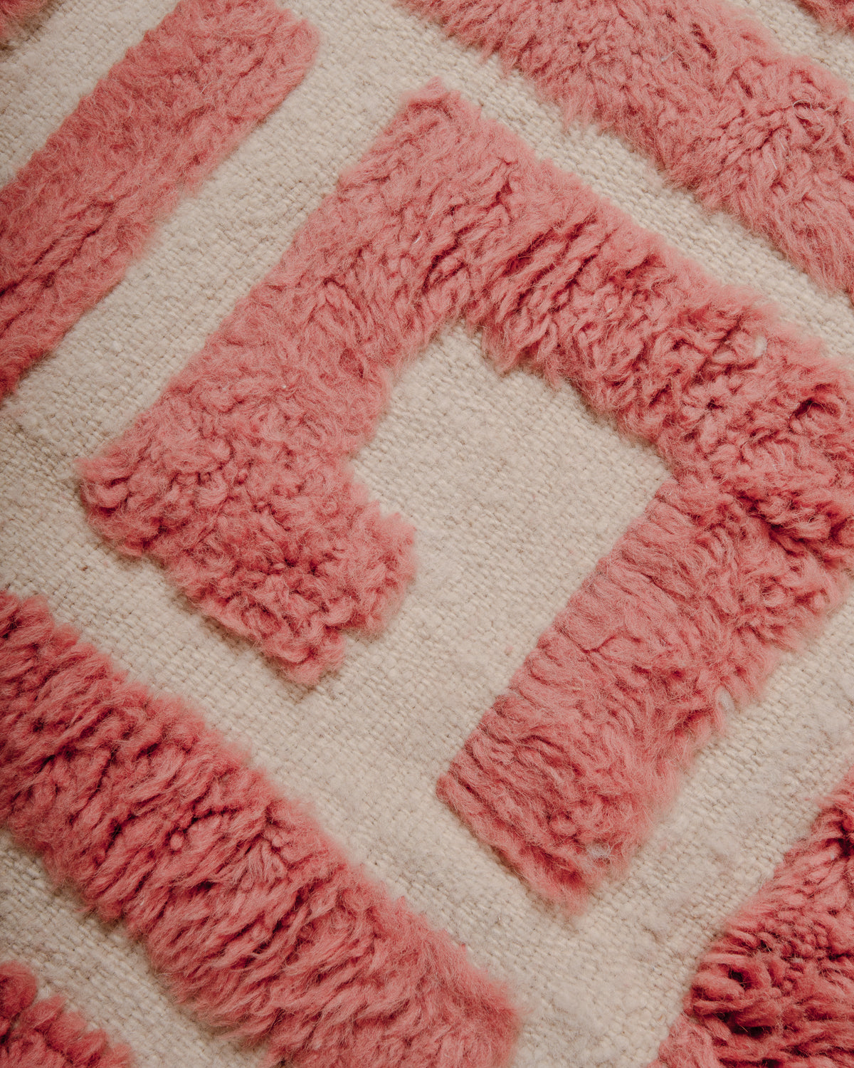 Detail of Berberlin Special Edition Beniourain rug with textural design made up of fluffy knotted wool pile in a soft dusty rose colour and flat woven base in natural cream.